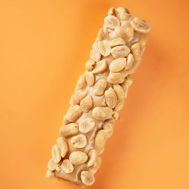 Unwrapped Payday candy bar over orange background